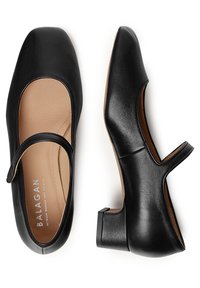 Ballerine in pelle nera con punta quadrata, cinturino e tacco basso a blocco. Presentano una soletta beige a contrasto con il marchio.