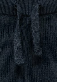 Mornarsko pleteno blago z teksturo, ki ima vrvico in rebrast pas. Tekstura je videti mehka in elastična.