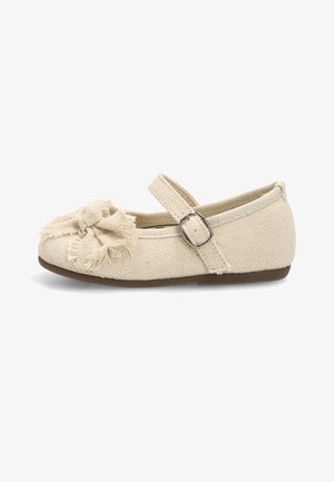 Zapato Mary Jane de tela beige con detalle de lazo deshilachado en la punta y una correa ajustable con hebilla plateada.