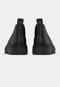 Μαύρες δερμάτινες μπότες μέχρι τον αστράγαλο με ματ φινίρισμα, ελαστικές πλαϊνές πάνελ και χοντρές, ανθεκτικές σόλες. Διπλοί ιμάντες στο τακούνι για εύκολη φορεσιά.