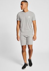 Grå t-shirt med kort ärm och matchande shorts i mjukt tyg, med en liten vit logotyp. Bärs med svarta träningsskor.