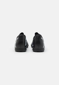 Zapatillas deportivas negras de material sintético texturizado, con acentos blancos contrastantes y un diseño de corte bajo. Suela de goma con relieve.