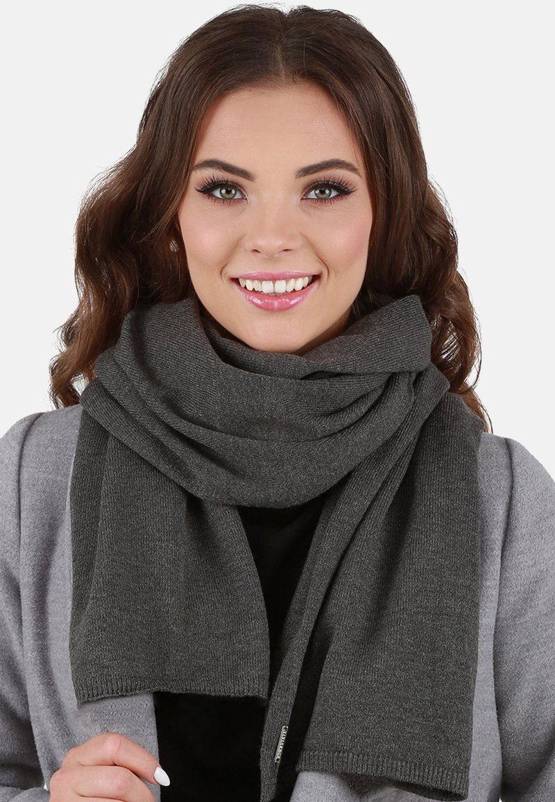 Bufanda gris oscuro hecha de material de punto, con una textura suave y un diseño sencillo, llevada de forma casual alrededor del cuello.
