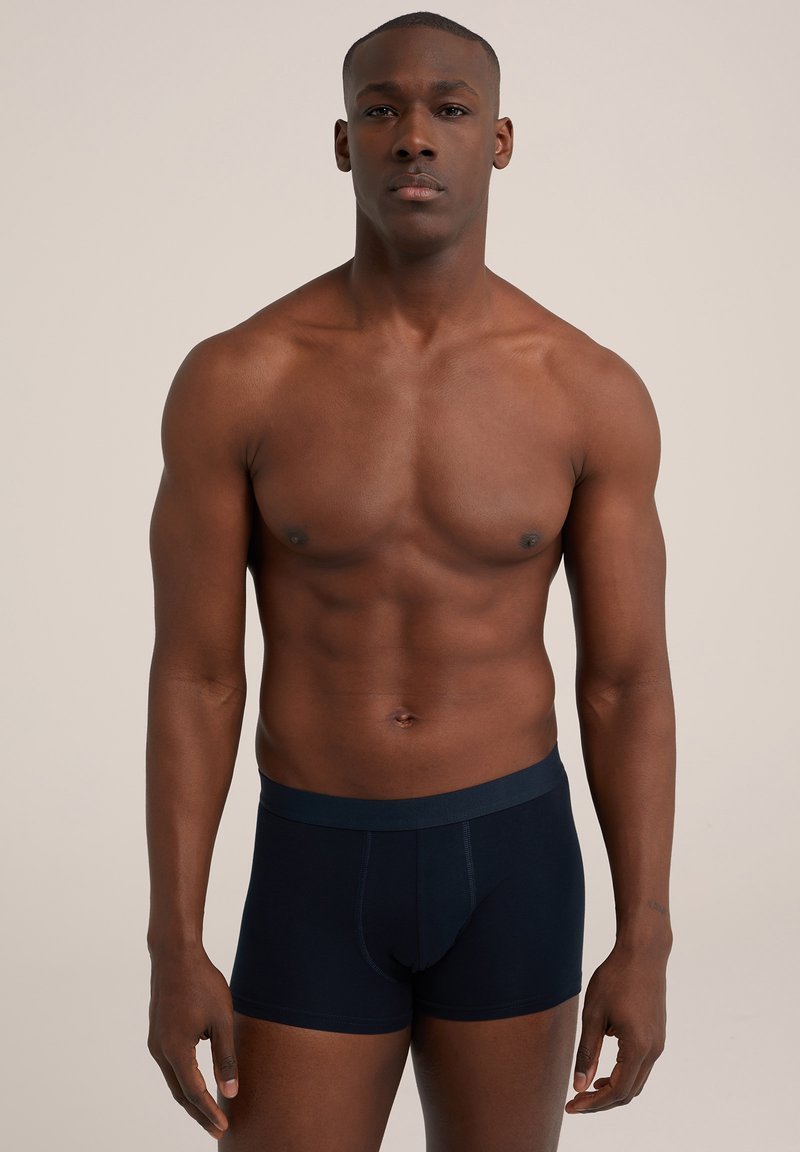 Tumši zili bokseršorti ar mīkstu jostasvietu. Audumam ir gluda tekstūra un pieguļošs dizains, kas izceļ elegantu siluetu.