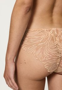 Bikini w kroju stringów w kolorze nude z koronką charakteryzuje się skomplikowanym kwiatowym wzorem, falbaniastym wykończeniem oraz bezszwowym tyłem dla jedwabiście gładkiego dopasowania.