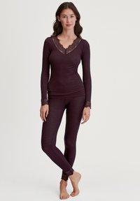 Haut long à manches ribbées couleur violet avec un col en dentelle, associé à des leggings assortis ornés de accents en dentelle au niveau des poignets. Texture douce, design ajusté.