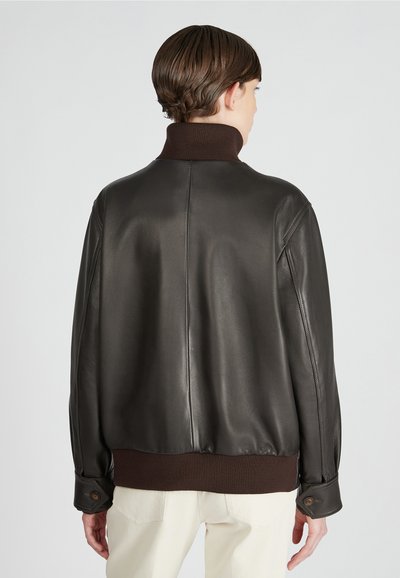 Braune Lederbomberjacke mit hohem Kragen, gerippten Bündchen und Saum. Glatte Textur, taillierte Passform und minimale Nähdetails.