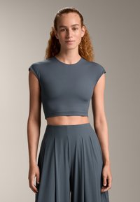 Gray crop top with short sleeves and a round neckline, paired with matching high-waisted pleated trousers, made from a smooth, stretchy fabric.