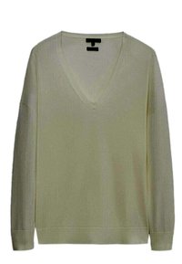 Maglione a V in giallo pallido, realizzato in tessuto morbido e leggero. Presenta maniche lunghe e una vestibilità rilassata con polsini e bordo a coste.