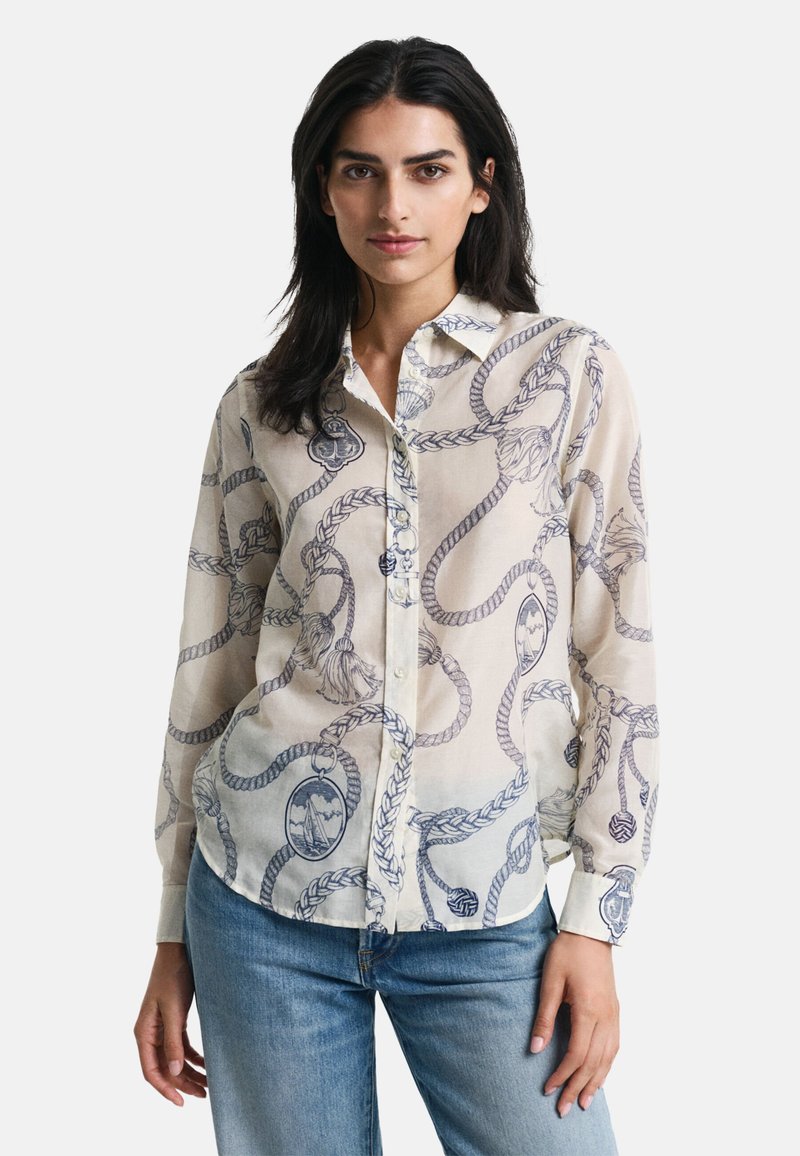 Leichte, cremefarbene Bluse mit einem blauen Seil- und Motivmuster, mit Knöpfen an der Vorderseite und langen Ärmeln, präsentiert vor einem weißen Hintergrund.