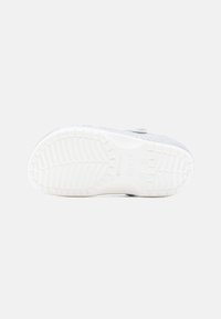 Szare buty wsuwane z teksturowaną cholewką, białą gumową podeszwą z wzorzystą powierzchnią oraz regulowanym paskiem. Minimalistyczny design o czystych liniach.