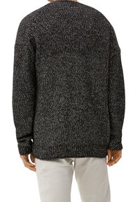 Maglione a maglia speckled bianco e nero con vestibilità ampia, spalle scese e polsini e orlo a coste. Texture liscia, dettagli minimi.