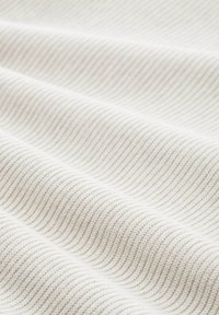 Tissu blanc légèrement texturé avec des lignes ondulées, présentant un motif doux et côtelé qui ajoute de la profondeur et de la dimension à la surface.