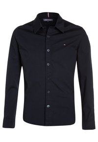 Camisa negra de manga larga con cuello clásico, cierre de botones en la parte delantera y pequeño logotipo en el lado izquierdo del pecho. Tejido de algodón suave.