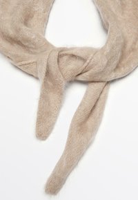 Sciarpa lavorata a maglia beige con una texture morbida e pelosa, caratterizzata da lunghe estremità annodate in modo sciolto. Il tessuto sembra leggero e caldo.