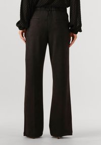 Zwarte wijde broek met een gladde textuur, voorzien van achterzakken en een getailleerde pasvorm. De tailleband is plat met een nette afwerking.