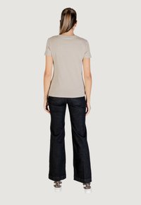 T-shirt beige a maniche corte abbinato a jeans neri a zampa. L'outfit è completato da sneakers bianche e calzini a fantasia.