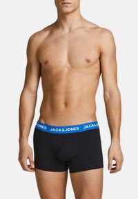 Boxer in cotone nero con un elastico blu in vita che presenta la scritta "JACK & JONES" ripetuta. Il tessuto è liscio e aderente.