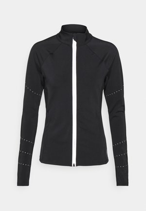 Veste de sport noire à manches longues avec fermeture éclair blanche à l'avant et petits points réfléchissants sur les manches, coupe ajustée, col haut.