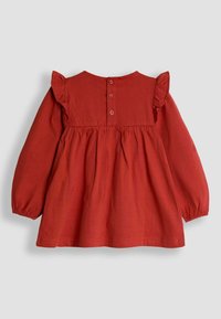 Rotes Baumwollkleid mit langen Ärmeln, Rüschendetails an den Schultern, Knopfverschluss auf der Rückseite und einer gerafften Taille für eine ausgestellte Form.