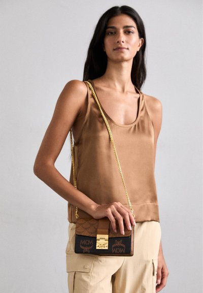Brown leather crossbody bag with gold chain strap, featuring logo patterns and a gold clasp. Compact rectangular shape, smooth and textured surfaces.
