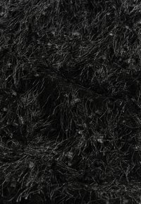 Tissu noir avec une apparence texturée et duveteuse, comportant de longues fibres fines et un motif complexe de brins entrelacés.