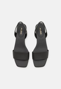 Sandali neri senza chiusura con punta quadrata, caratterizzati da una larga striscia opaca e una sottile cinghia sul retro. La soletta è impresso con "ALDO."