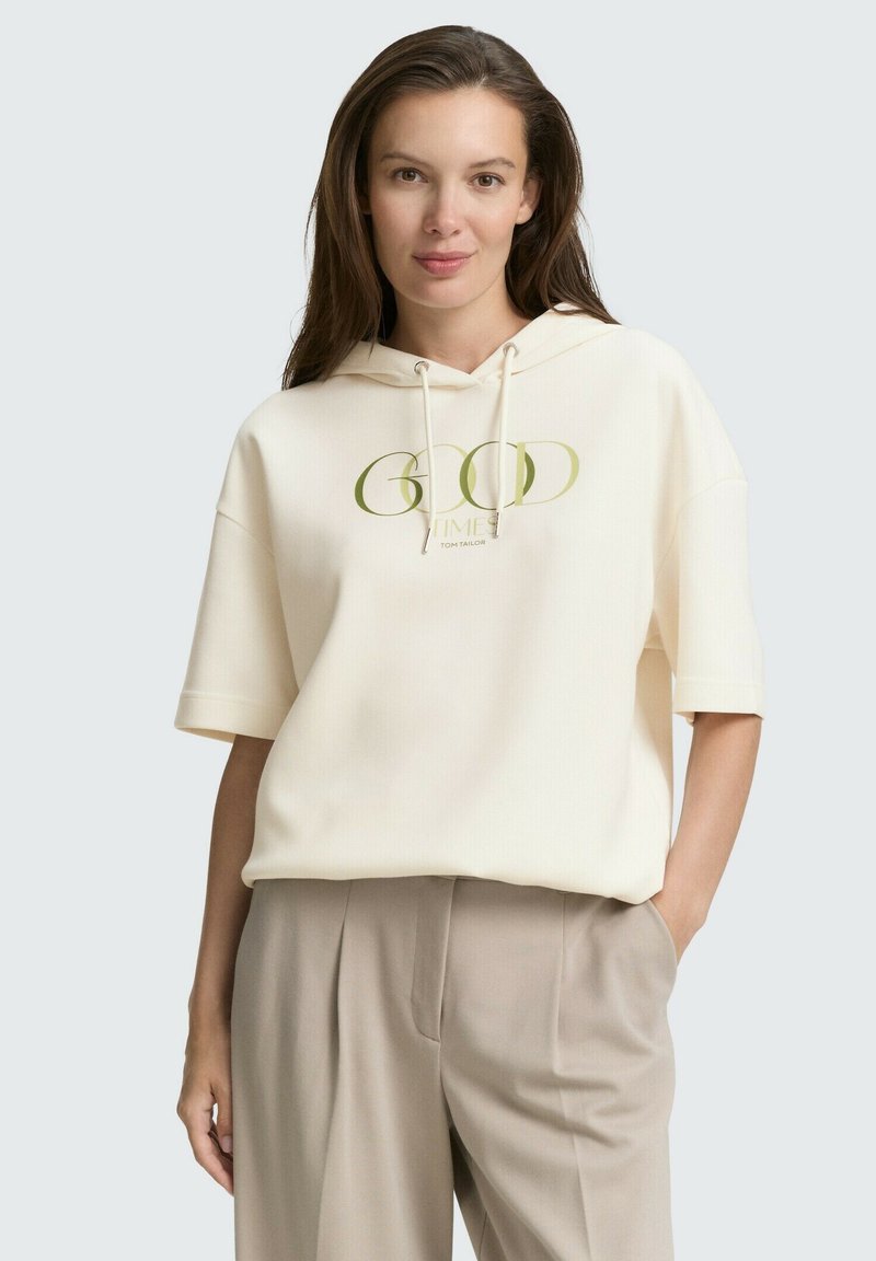 Helle Kapuzenjacke mit einem Frontdruck in grüner Schrift. Weicher Stoff, lässiger Schnitt, kurze Ärmel und Kordelzugkapuze.