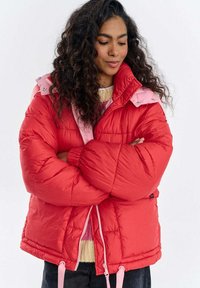 Czerwona kurtka puchowa z różowym kołnierzem, z zamkiem błyskawicznym, elastycznymi mankietami i regulowanym dołem. Pikowana tekstura i ciepłe, wyściełane wykonanie.