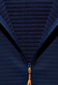 Navy zip-up jacket featuring ribbed texture at the collar area, orange zipper string detail, and soft knit fabric throughout.