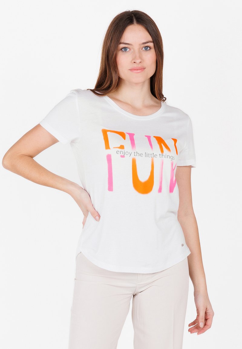 T-shirt bianca in cotone con scollatura rotonda, decorata con grande testo multicolore: "DIVERTIMENTO" in arancione e rosa, e la frase sottostante in grigio.