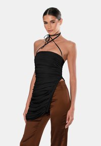 Mustahi taulukotoodang musta ruched halter-top, millel on tekstuuriga viimistlus ja lipsuga sulgemine, koos pruuni satiinist pükstega, millel on sile ja läikiv pind.