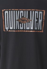 Black t-shirt featuring a prominent silver and copper "Quiksilver" logo with a textured diamond shape and flat design outline.