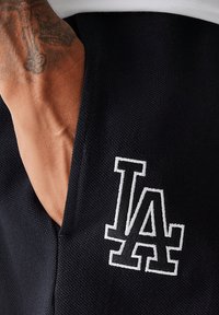 Jogger in tessuto navy con finitura testurizzata, dotato di un logo "LA" ricamato in bianco sulla tasca e cuciture rinforzate per una maggiore durabilità.