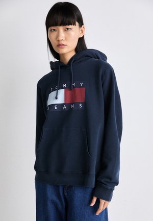 Felpa con cappuccio blu navy con tasca frontale, caratterizzata da un design grafico del logo in rosso, bianco e blu. Realizzata in tessuto morbido con polsini a costine.