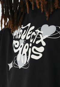 Zwarte sweatshirt met een opvallend wit grafisch ontwerp met de tekst "PROJECT PARIS", versierd met harten en steraccenten in verschillende grijstinten.