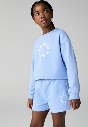 Ljusblå cropped sweatshirt och matchande shorts, gjorda av mjukt material. Har vit logotyptryck på framsidan och shortsen. Avslappnad passform.