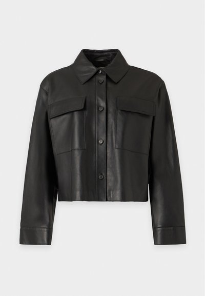 Black cropped leather jacket with long sleeves, button front, pointed collar, and two flap chest pockets against a plain background.