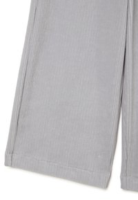 Pantaloni in velluto a coste grigio chiaro con la trama a coste verticali, che mostrano la parte inferiore della gamba e l'orlo su sfondo bianco.