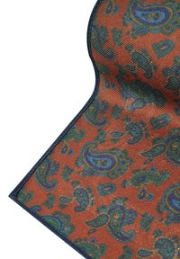 Dywan w wzór paisley w odcieniach pomarańczowym i zielonym, z misternymi wzorami w niebieskich akcentach i ciemnoniebieską bordurą. Miękka tekstura powierzchni.