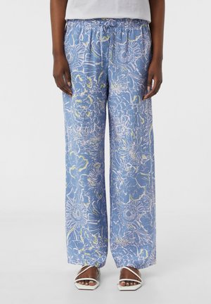 Lichtblauwe wijde broek met bloemenprint in wit en groen. Voorzien van een elastische tailleband en een zachte stoftextuur. Casual ontwerp.
