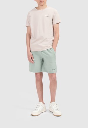 Lichtbeige crewneck t-shirt met subtiele logo, gecombineerd met mintgroene shorts en witte sneakers met textuuraccenten.