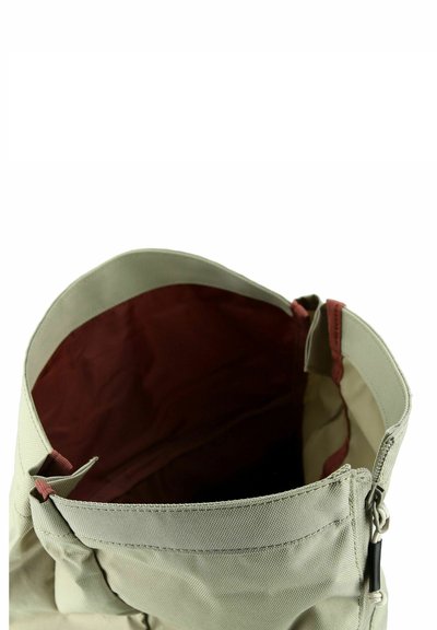 Zaino in tessuto beige con fodera interna color bordeaux e una zip nera, mostrato aperto dall'alto.