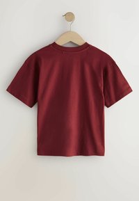 Bordeaux katoenen t-shirt met korte mouwen, ronde halslijn en een gladde textuur, hangend aan een houten hanger tegen een neutrale achtergrond.