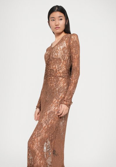 Robe en dentelle marron avec des manches longues et un décolleté en V. Motif floral transparent, silhouette ajustée et détails froncés sur les côtés.
