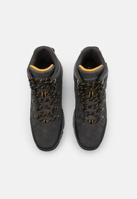 Stivali da trekking neri realizzati in suede e rete, con dettagli arancioni, sistema di lacci robusto e supporto alto per la caviglia progettato per la durabilità.