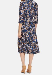 Blå och brun leopardmönstrad klänning i lätt tyg, med omslagdesign, trekvartslånga ärmar och knälång kjol.