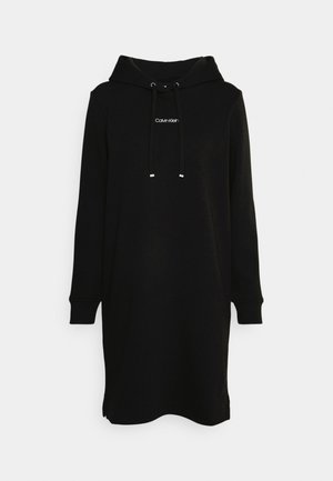 Zwarte, lange mouwen, capuchonjurk met koordjes aan de voorkant en het "Calvin Klein"-logo zichtbaar in het midden van de borst tegen een effen achtergrond.