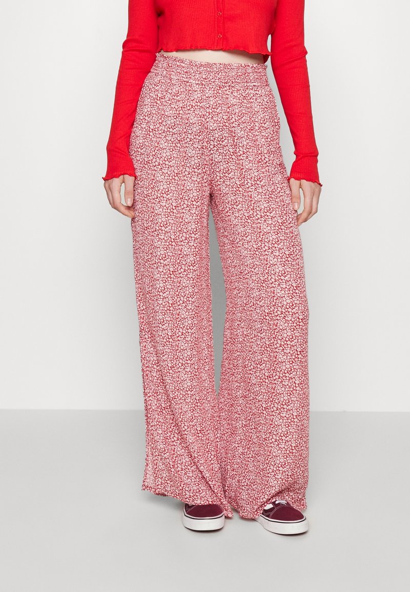Wide-leg trousers in a red and white floral pattern, made from lightweight fabric with an elastic waistband and a relaxed fit.