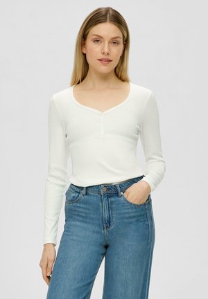 Witte longsleeve top met een ronde hals en drie knopen aan de voorkant, gecombineerd met blauwe denim jeans met een relaxte pasvorm en zakken.